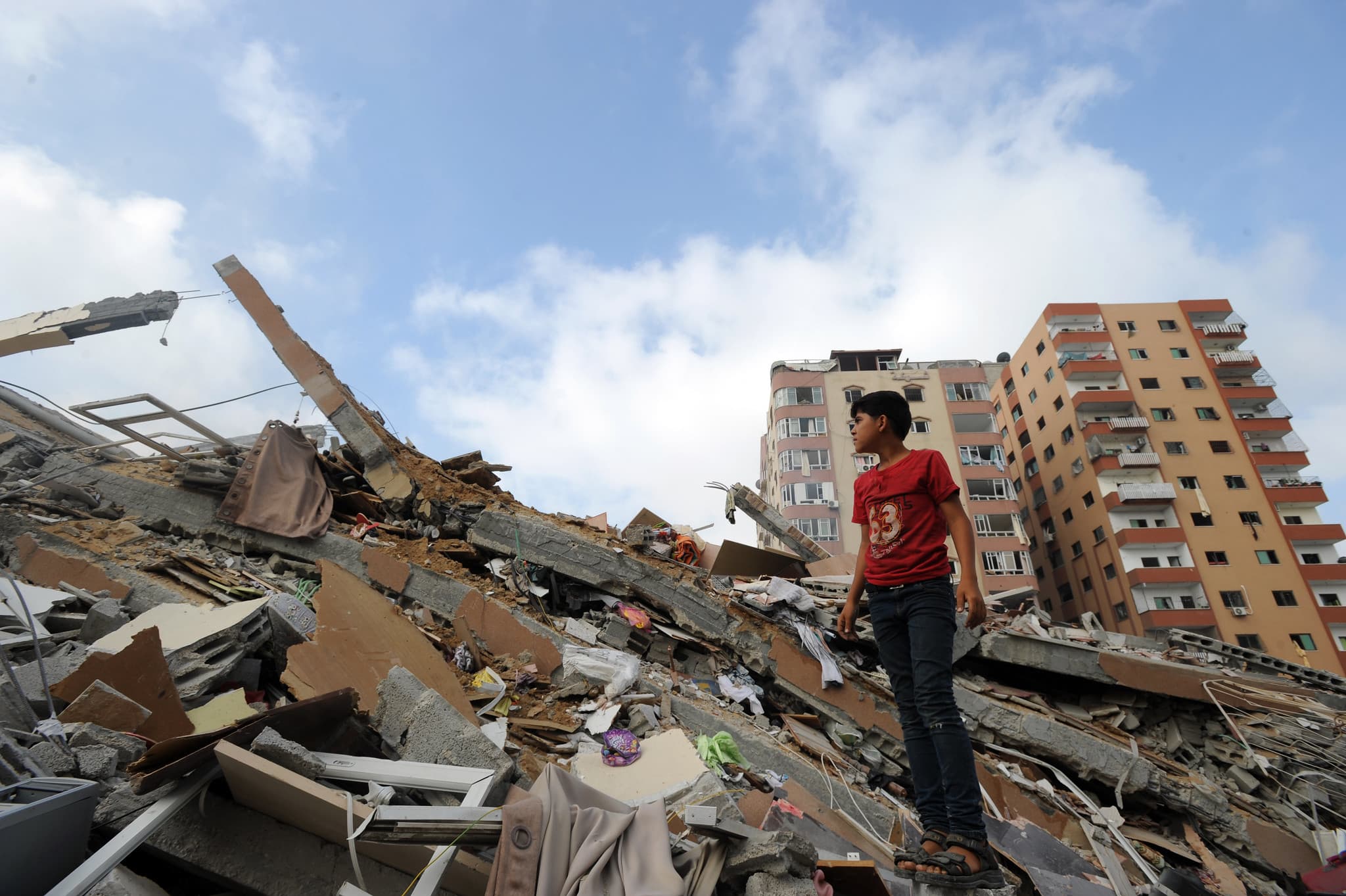 Palestinians collect their belongings from under the rubble of a residential tower, which witnesses said was destroyed by an Israeli air strike in Gaza City on Aug. 24, 2014. (UN Photo/Shareef Sarhan)