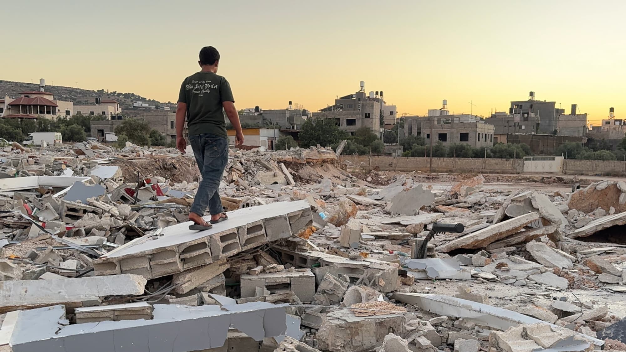 A Palestinian boy walks atop the rubble of a shop destroyed by Israeli forces near the occupied West Bank city of Jenin. (Mohammed Turkman/MEE)