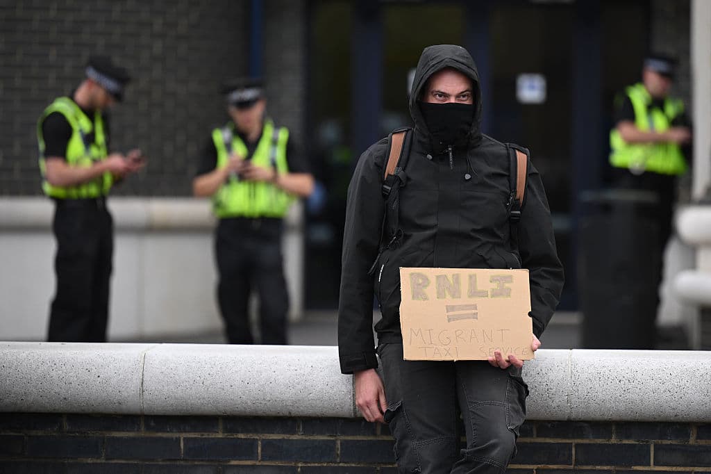 A Patriot Platform protester holds a sign saying "RNLI = Migrant Taxi Service" at the RNLI station in Poole on 9 September 2026
